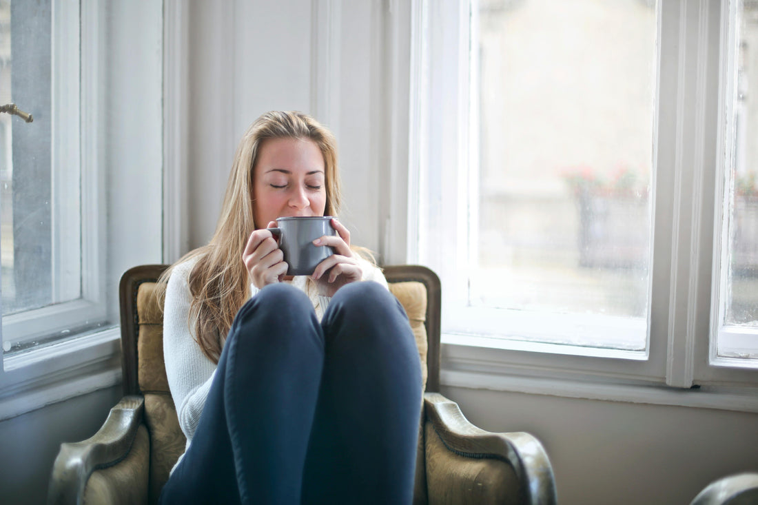 Woman reading handwritten letter by warm lamplight with a cup of tea - cozy mystery storytelling experience